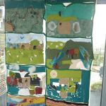 A colourful textile wall hangings of greens and blues depicting landscapes.